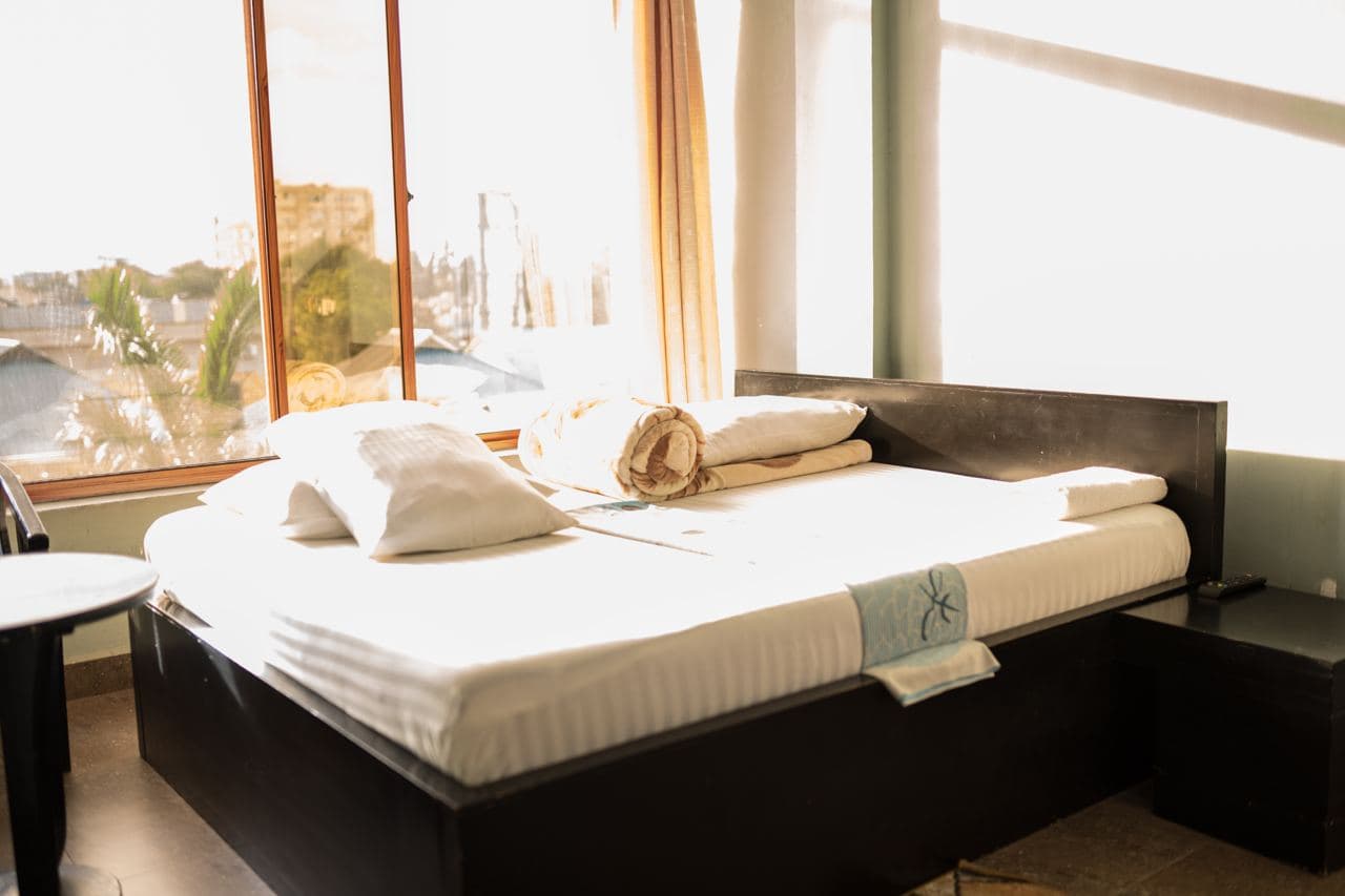 Double bed with fresh linen beside a sunlit window
